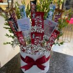 Premium Custom Bloom Chocolate Box with fresh baby breath flowers and assorted chocolates including KitKat, Twix, Mars, and Bounty, beautifully arranged in a white round gift box by Giftyfy