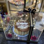 Black acrylic cake box with custom message, fairy lights, and fresh roses for delivery in Pakistan