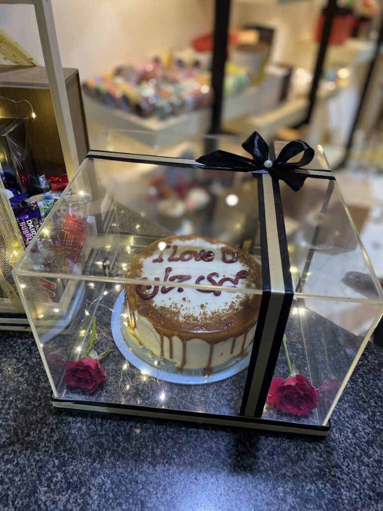 Black acrylic cake box with custom message, fairy lights, and fresh roses for delivery in Pakistan