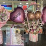 Pink birthday gift set with fresh flower bouquet, custom name balloons, and acrylic cake box with LED letter in Pakistan